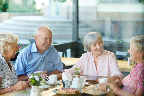 Happy seniors sitting by table and talking at leisure